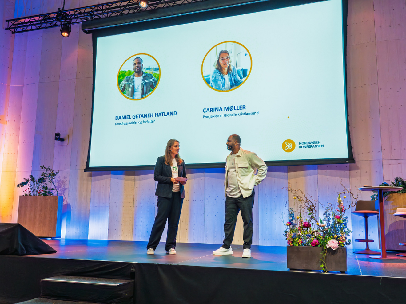 Carina møller og Daniel Getaneh Hatland står på scenen foran publikum på Nordmørskonferansen. 