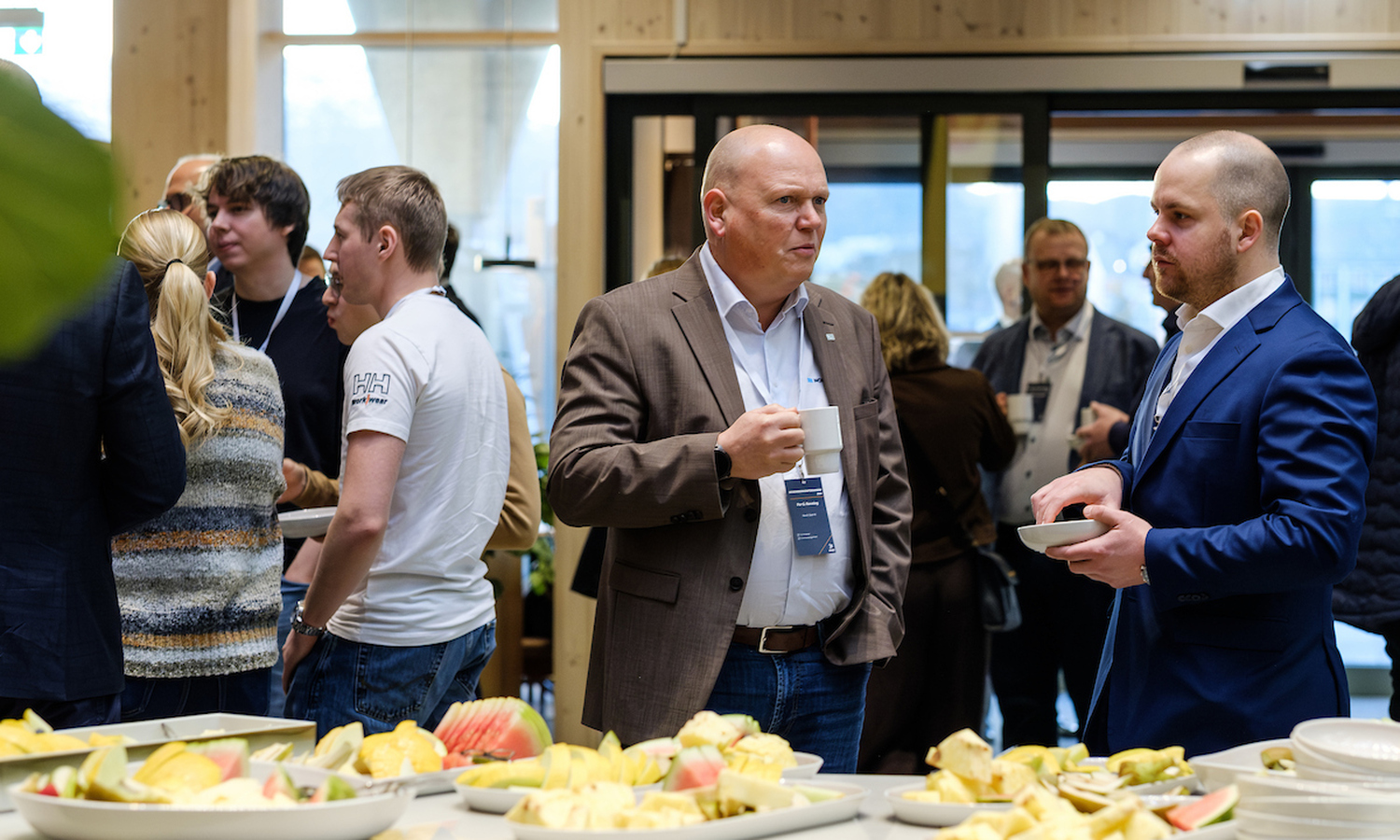 Mennesker snakker sammen foran en rekke fruktfat 