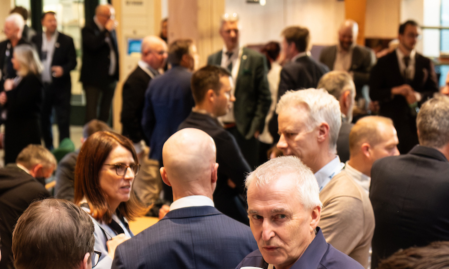 Mennesker snakker sammen i en full aula