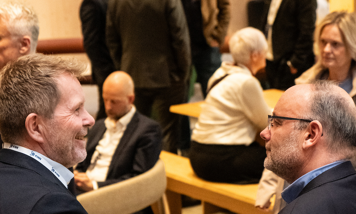 Mennesker snakker sammen i en full aula
