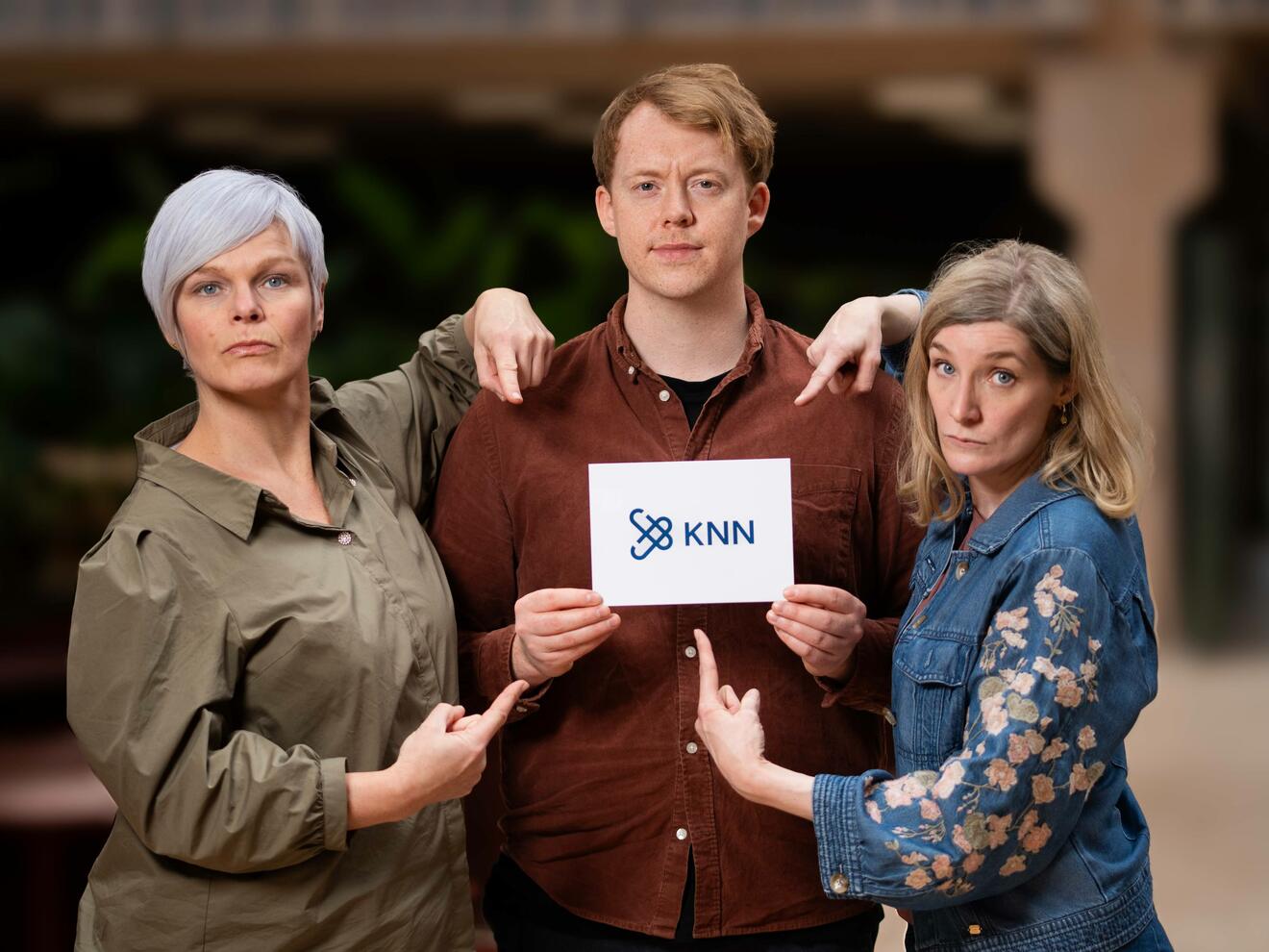 Tre mennesker med overdrevent alvorlig mine peker mot et ark der det står KNN