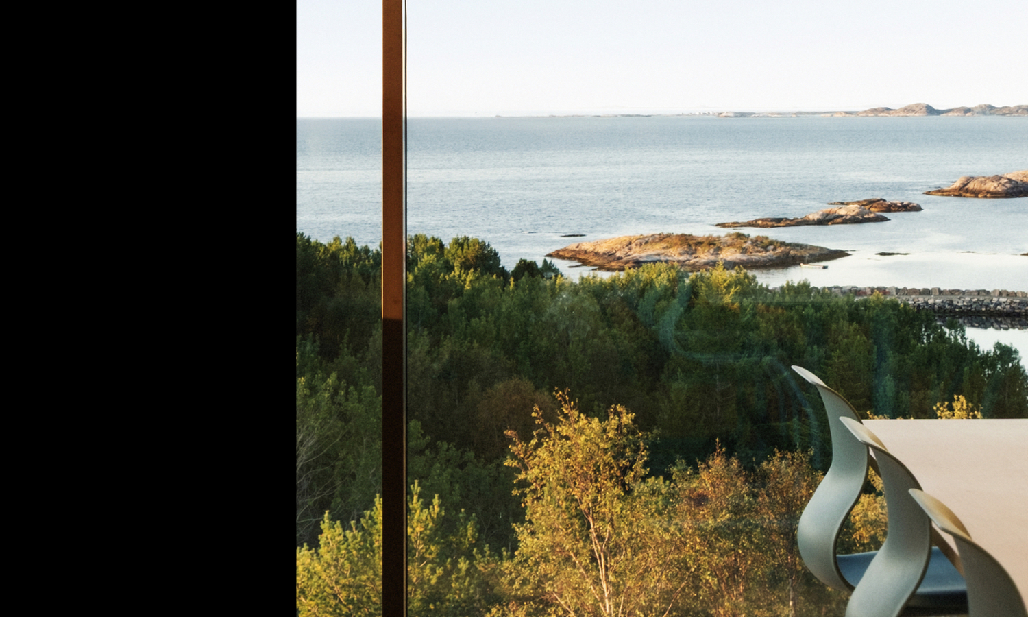 stoler i rekke langs et bord i forgrunnen, i bakgrunnen kan en se have