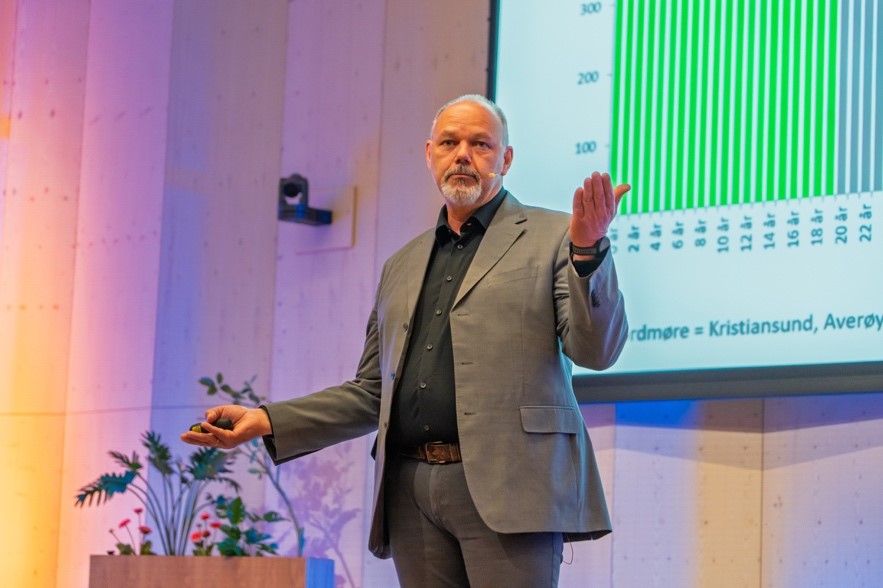 Statistikksjef Ulf Andersen fra NAV pekte på utviklingstrekk som treffer Nordmøre hardt: Færre i arbeid, flere eldre – og mange som står utenfor. Her med befolkningsprognosene for regionen. Foto: Heine Schjølberg Foto av presentasjon på scene
