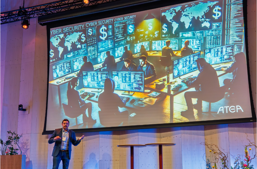 Vegard Kjerstad fra Atea ga deltakerne et unikt innblikk i et reelt hackerangrep – og hvordan norske virksomheter kan gjøre sikkerhet til et konkurransefortrinn. Foto: Heine Schjølberg Foto av presentasjon på scene