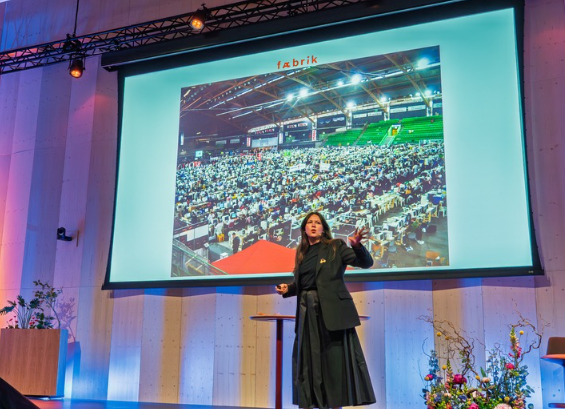 På lerret bak henne vises et bilde fra The Gathering i Hamar – en av verdens største datatreff. – Se for deg flere hundre mennesker som sitter ogsyr sammen en hel helg, hadde Jenny Skavlan sagt med engasjert stemme og gnist i øyet. – To uker etterpå booket jeg Vikingskipet på Hamar og fikk jobben som daglig leder i bærekraftselskapet, fortalte Karoline Kjønniksen, CEO i Fæbrik. Foto av presentasjon på scene
